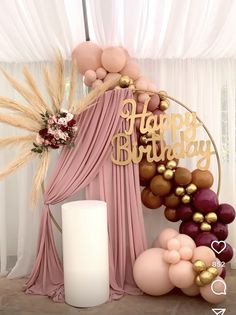 a happy birthday sign surrounded by balloons and other decorations in front of a drape