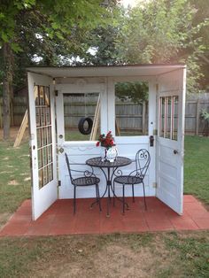 a small white shed with a table and chairs