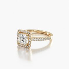 a yellow gold engagement ring with a square cut diamond surrounded by pave set diamonds