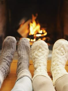 three feet in socks sitting next to a fire