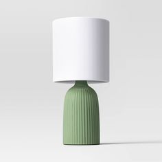 a green table lamp with a white shade on the top and bottom part of it