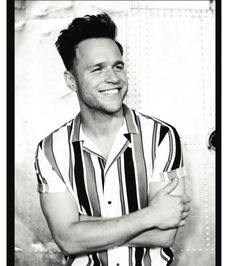 a black and white photo of a man with his arms crossed smiling at the camera