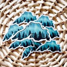 a sticker with the shape of a lake surrounded by trees and mountains on it