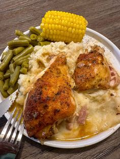 a white plate topped with chicken, mashed potatoes and corn on the cob