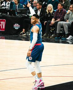 a man standing on top of a basketball court wearing a blue jersey and white pants