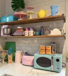 a kitchen counter topped with lots of colorful dishes and cups on top of shelves next to a potted plant