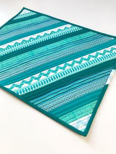 a piece of blue and green quilted material on a white table top with scissors