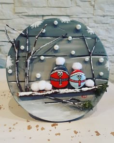 two birds are sitting on a branch in front of a brick wall with snow and branches