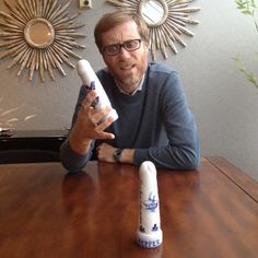 a man sitting at a table with two candles in front of him and the candle is on top of it