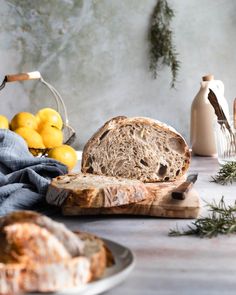 a loaf of bread sitting on top of a wooden cutting board next to lemons