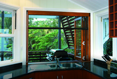 a kitchen with a sink, stove and window in it's center area that looks out onto the trees outside