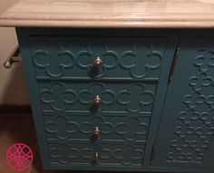 a bathroom vanity with an ornate design on the front and side drawers, along with a marble counter top