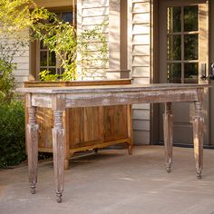 a wooden table sitting on top of a patio next to a building with doors and windows