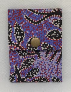 a purple, black and red patterned wallet with a gold button on the front pocket