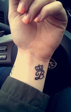 a woman's wrist tattoo with the letter b on her left hand and an arrow in the middle