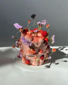 a pink cake with strawberries and flowers on it