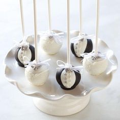 some cake pops are sitting on a plate with white and black candies in them