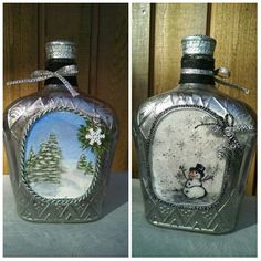 two glass bottles decorated with snowmen and pine trees, one has a silver ribbon around the top