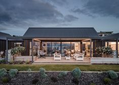 an outdoor living area with patio furniture and potted plants on the lawn at dusk