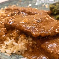 a plate with rice, meat and broccoli covered in brown gravy