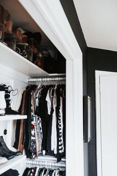 an open closet with clothes and shoes on the shelves, next to a white door