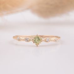 a close up view of a ring with a green stone in the middle and white diamonds on it