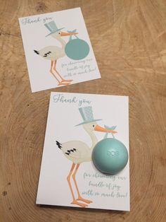 two cards with storks on them are next to a ball