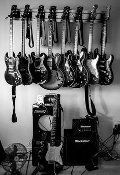 guitars and amps are lined up on the wall next to each other in black and white