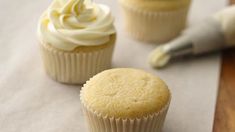 two cupcakes sitting next to each other on top of a table with icing