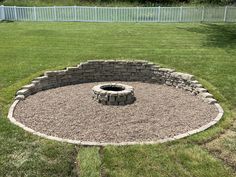 an outdoor fire pit surrounded by gravel and grass