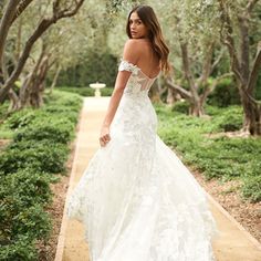 a woman in a wedding dress walking down a path