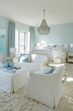 a living room filled with white furniture and blue walls