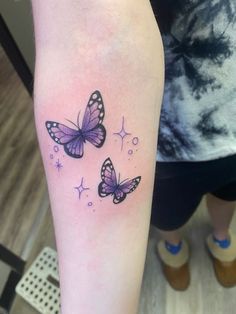 two purple butterflies on the left arm and one is black with white dots in it