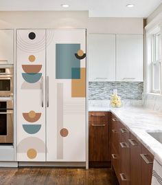 a kitchen with white cabinets and an abstract painting on the side of the cabinet door