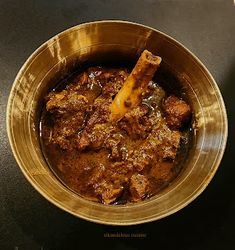 a bowl filled with meat and sauce on top of a table next to a plate