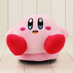 a pink stuffed animal with big eyes sitting on the floor