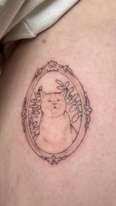 a cat tattoo on the back of a woman's stomach with an oval frame around it