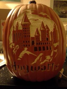 a carved pumpkin with an image of hogwart's castle in the center and birds flying around it