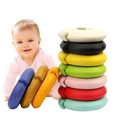 a baby laying on the ground next to a stack of colorful toy items in front of a white background