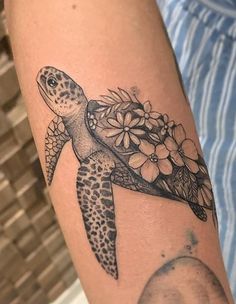 a tattoo with a turtle and flowers on it