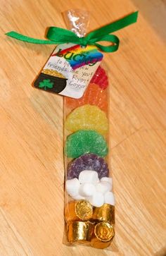 a candy bar filled with gummy bears on top of a wooden table next to a green ribbon