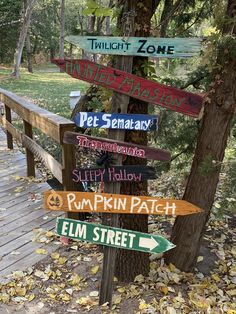 a wooden sign post with many different signs on it's sides and trees in the background