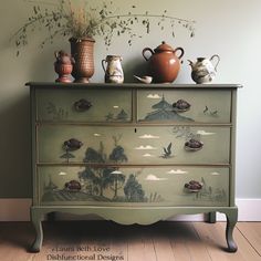 a green dresser with two vases on top of it