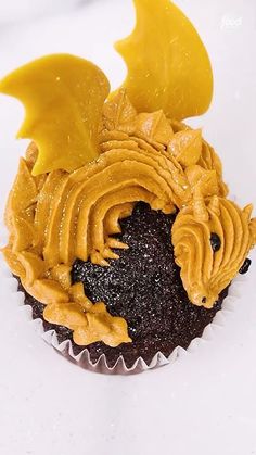 a cupcake with yellow frosting and dragon decorations