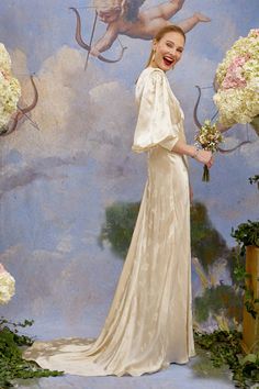 a woman standing in front of a painting holding flowers