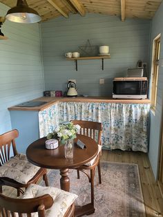 a small kitchen with blue walls and wood floors, along with an old fashioned dining table