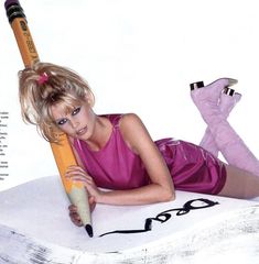 a woman laying on the ground holding a giant pencil