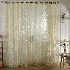 the curtains in this room are white and have floral designs on them, as well as flowers