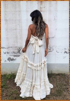 a woman standing in front of a white wall wearing a dress with ruffles