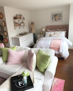 a white couch sitting in a living room next to a bed with lots of pillows on top of it